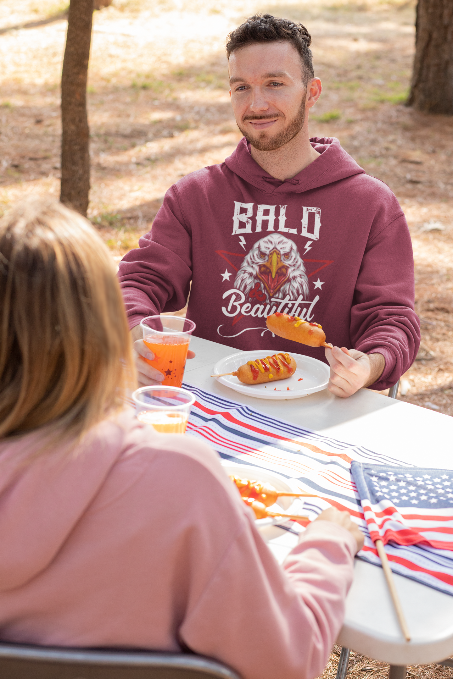 Man eating a corn dog wearing maroon hoodie