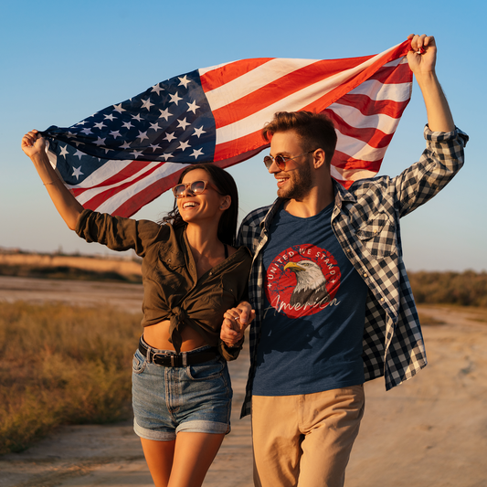 Couple walking down dirt road holding American flag over their heads